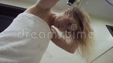 漂亮的女人在浴室洗澡后用吹风机吹干头发。